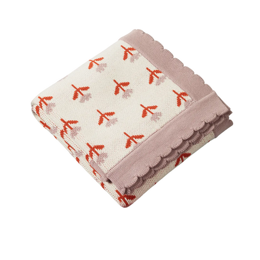 A folded knit blanket with a scalloped edge, featuring a cream background with a pattern of small red and dusty pink flowers, and a solid dusty pink border.